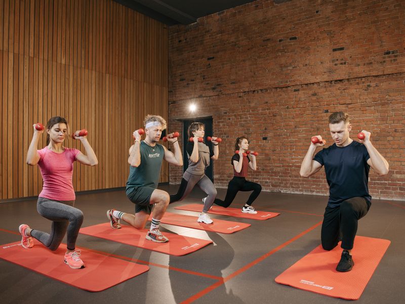 Group exercising together with dumbbells on mats